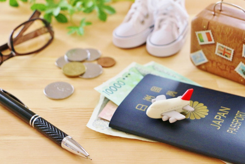 飛行時のおもちゃパスポートカバン白いスニーカーや小銭メガネペンの旅行をイメージした画像